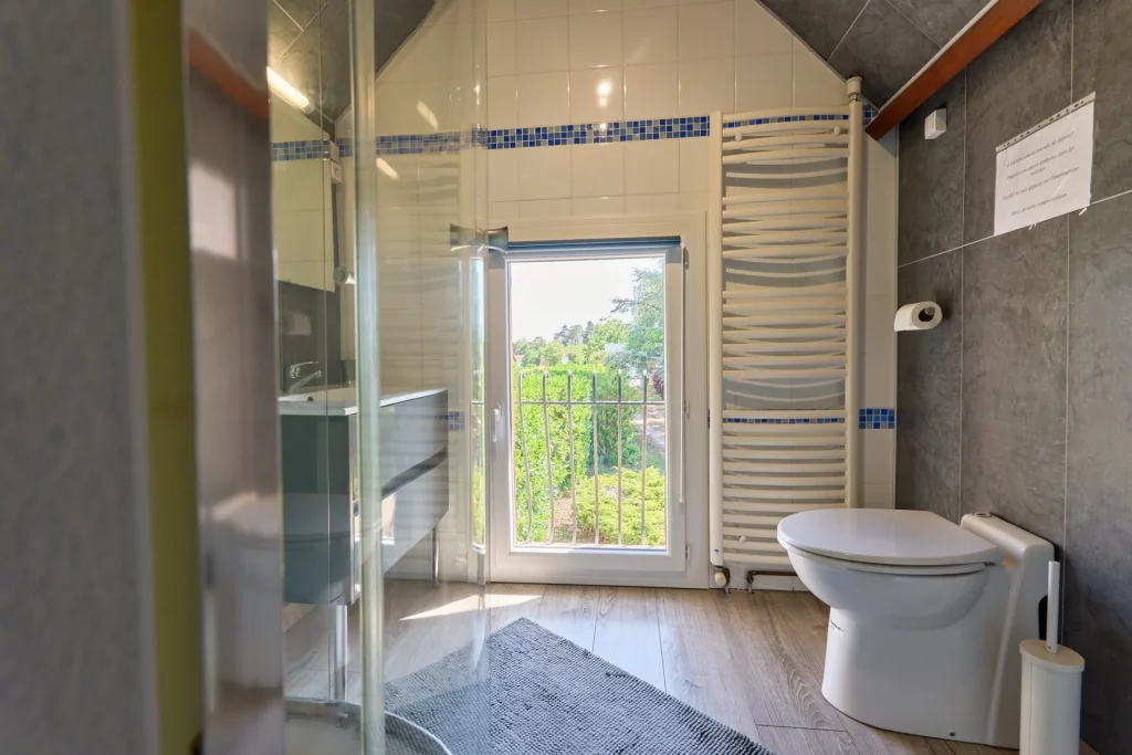 Vue d'ensemble de la salle de bain avec cabine de douche, vasque et WC, sèche, serviette électrique